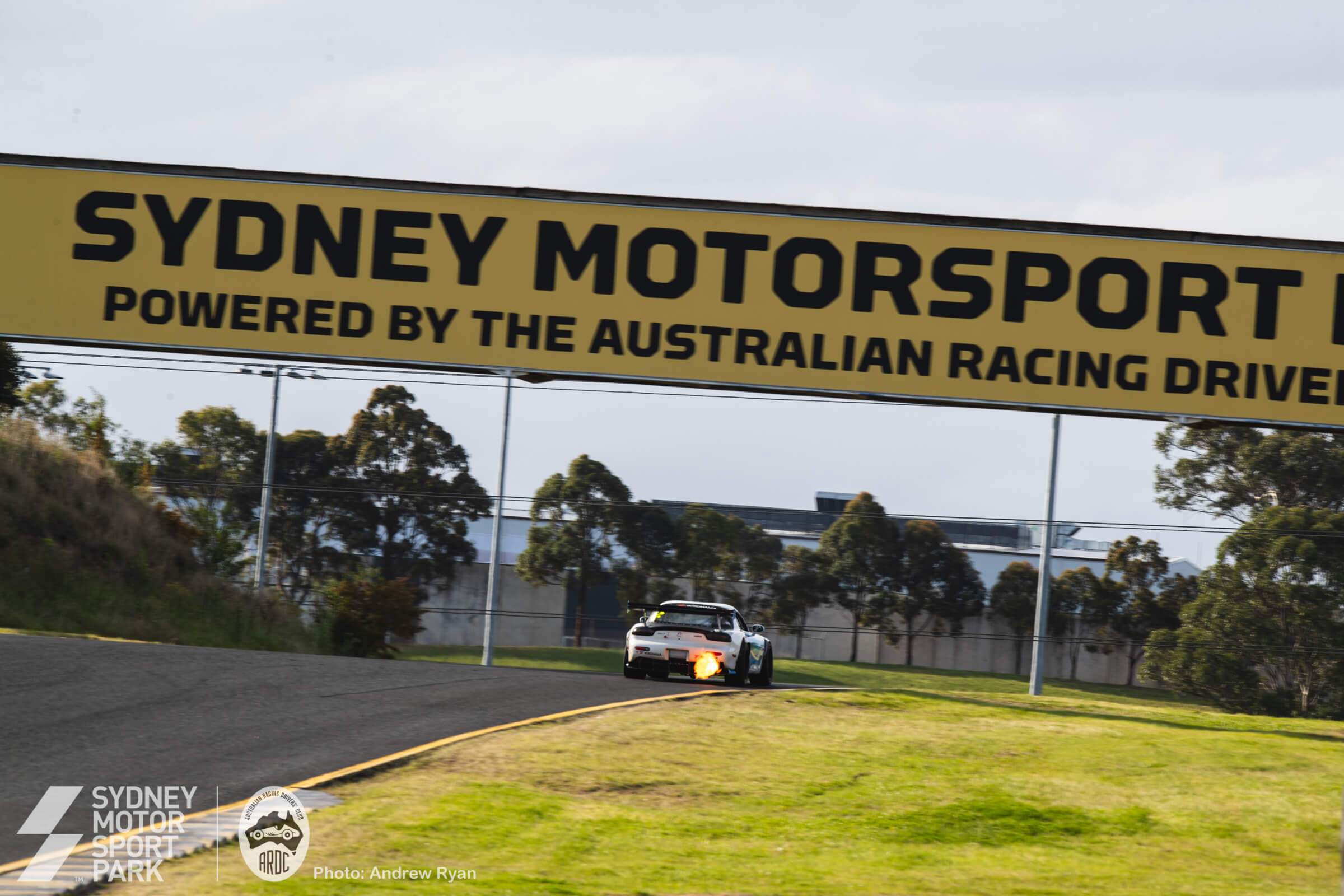 A time-attack build spitting flames under the Sydney Motorsport Park bridge
