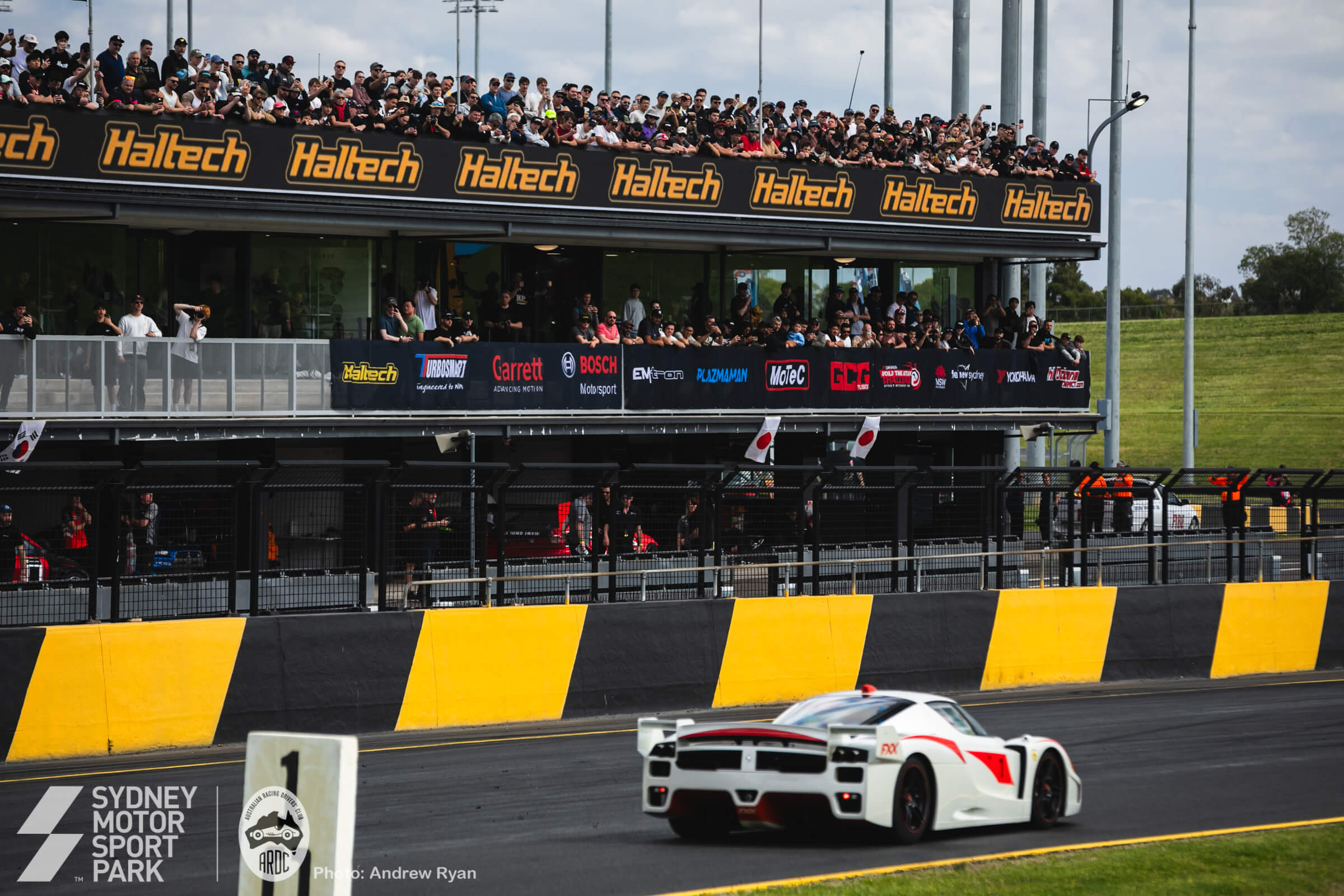 A Ferrari FXX passing the packed main grandstand